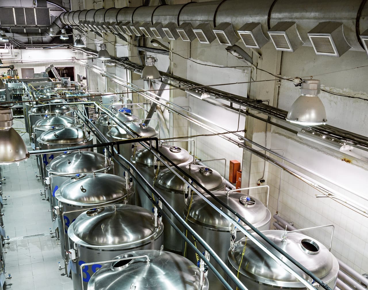 Rangée de cuves en inox reliées par des tuyauteries, dans un atelier de production